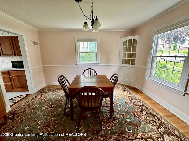 841 Huntington Rd, East Lansing, MI 48823 - dining room with a chandelier, plenty of natural light, light wood-style floors, ornamental molding, and baseboards