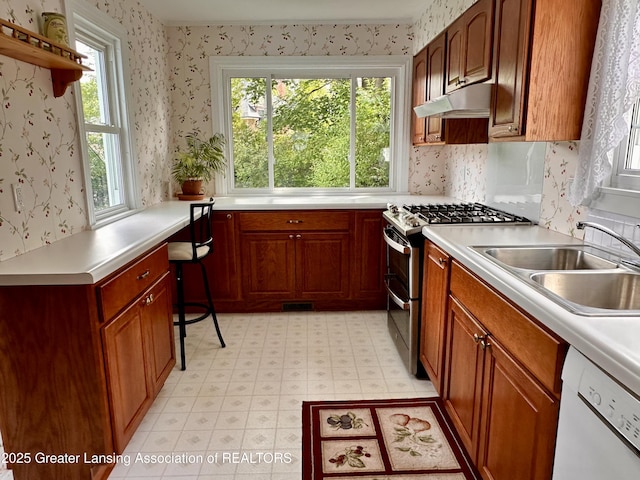 841 Huntington Rd, East Lansing, MI 48823 - kitchen featuring double oven range, dishwasher, a sink, under cabinet range hood, and wallpapered walls