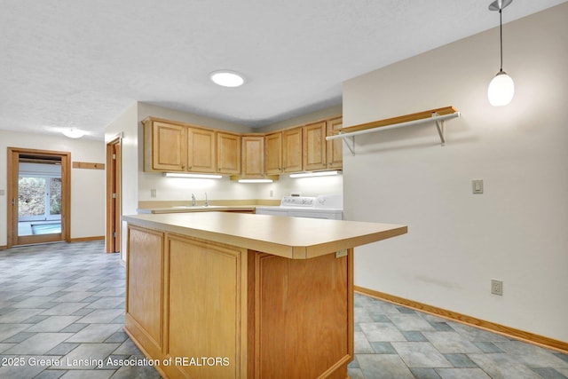345 Linn Rd, Williamston, MI 48895 - kitchen featuring light countertops, a kitchen island, washer and dryer, pendant lighting, and light brown cabinetry