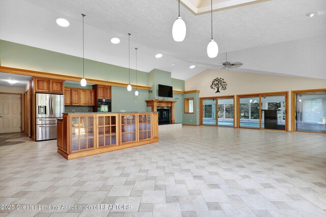 345 Linn Rd, Williamston, MI 48895 - kitchen with stainless steel refrigerator with ice dispenser, open floor plan, black oven, brown cabinets, and high vaulted ceiling
