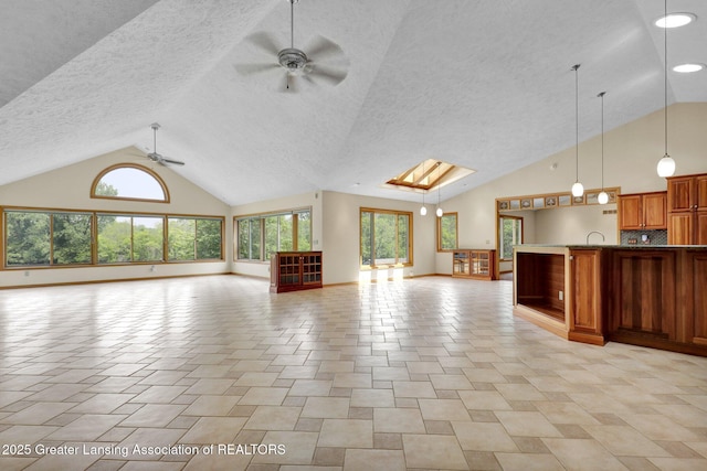 345 Linn Rd, Williamston, MI 48895 - unfurnished living room with ceiling fan, high vaulted ceiling, plenty of natural light, a textured ceiling, and a skylight