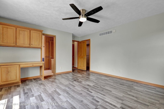 345 Linn Rd, Williamston, MI 48895 - unfurnished bedroom with built in desk, light wood-style floors, a textured ceiling, and ceiling fan