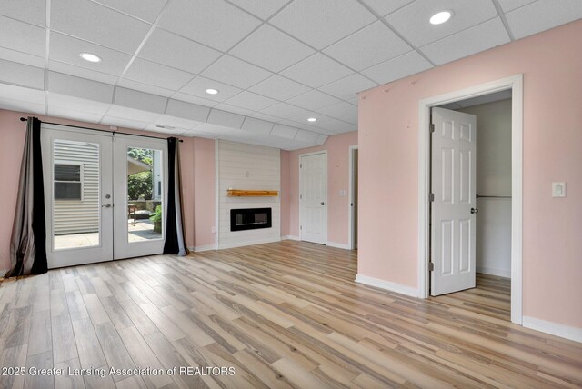345 Linn Rd, Williamston, MI 48895 - unfurnished living room featuring light wood-style flooring, french doors, a paneled ceiling, a large fireplace, and recessed lighting