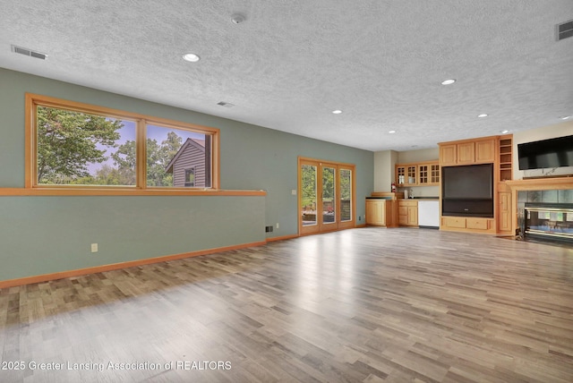 345 Linn Rd, Williamston, MI 48895 - unfurnished living room with a textured ceiling, recessed lighting, light wood-type flooring, and a tiled fireplace