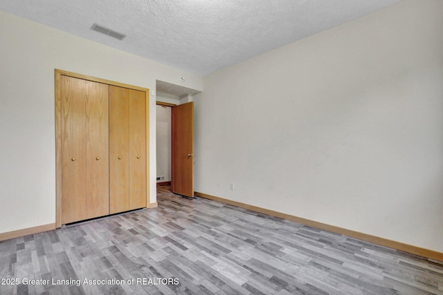 345 Linn Rd, Williamston, MI 48895 - unfurnished bedroom with light wood-type flooring, a textured ceiling, and a closet