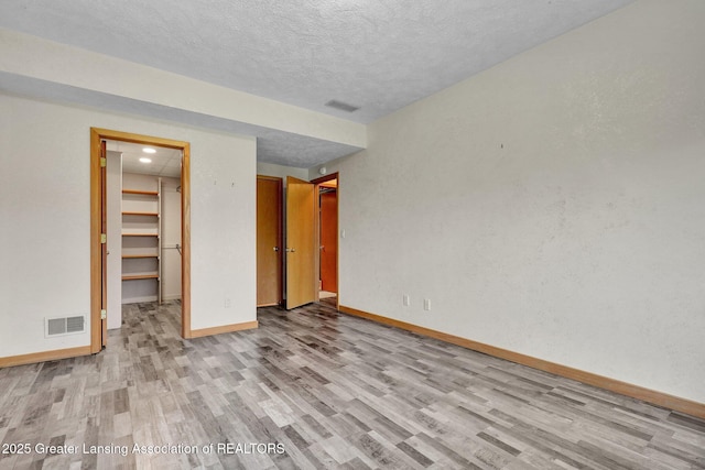 345 Linn Rd, Williamston, MI 48895 - unfurnished bedroom featuring wood finished floors, a textured ceiling, a walk in closet, and a closet