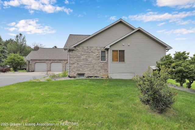 345 Linn Rd, Williamston, MI 48895 - view of side of property featuring a garage, concrete driveway, brick siding, and a yard