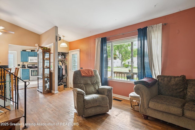 4622 Burchfield Ave, Lansing, MI 48910 - living area featuring light wood finished floors, vaulted ceiling, baseboards, and stairway