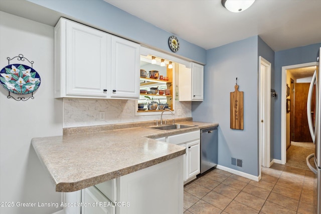 10470 Barnes Hwy, Eaton Rapids, MI 48827 - kitchen with stainless steel dishwasher, a sink, decorative backsplash, white cabinets, and a peninsula
