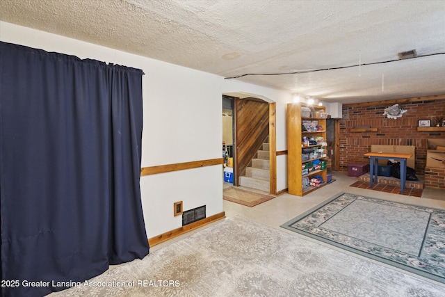 10470 Barnes Hwy, Eaton Rapids, MI 48827 - living room featuring a textured ceiling, stairs, brick wall, and arched walkways