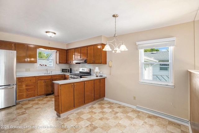4810 Cherryland Dr, Lansing, MI 48910 - kitchen with stainless steel appliances, under cabinet range hood, brown cabinets, light countertops, and a baseboard radiator