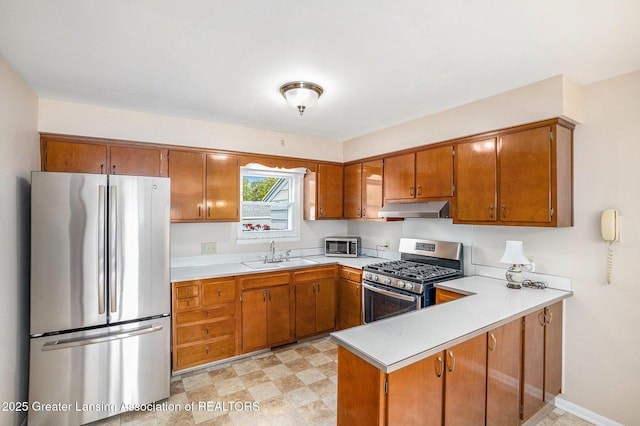 4810 Cherryland Dr, Lansing, MI 48910 - kitchen with appliances with stainless steel finishes, under cabinet range hood, a sink, brown cabinets, and light countertops