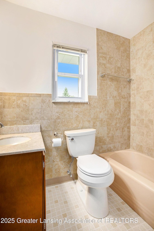 4810 Cherryland Dr, Lansing, MI 48910 - full bathroom featuring toilet, tile walls, vanity, tile patterned floors, and washtub / shower combination