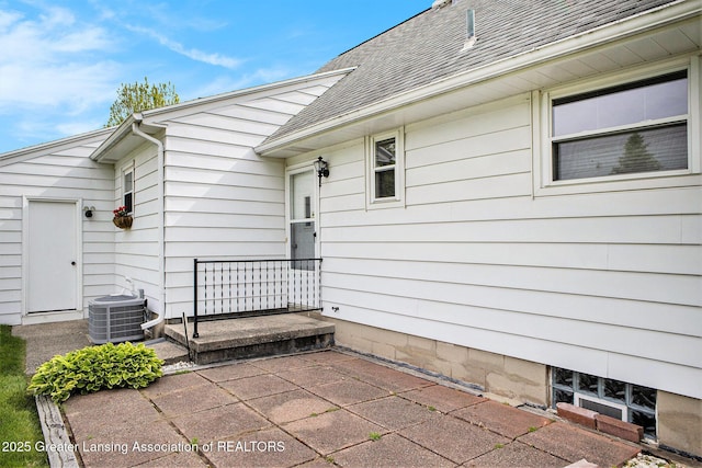 4810 Cherryland Dr, Lansing, MI 48910 - property entrance with cooling unit, a shingled roof, and a patio