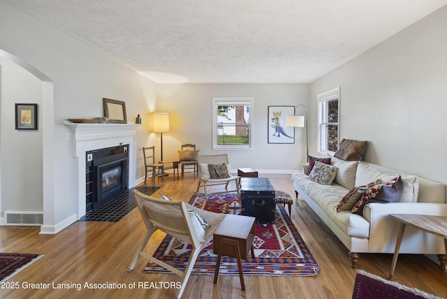 438 Bailey St, East Lansing, MI 48823 - living area with wood finished floors, a fireplace, a textured ceiling, arched walkways, and baseboards