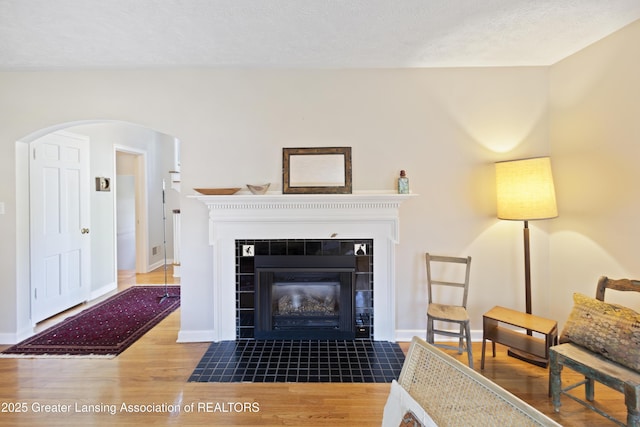 438 Bailey St, East Lansing, MI 48823 - living room with wood finished floors, a tiled fireplace, arched walkways, and baseboards