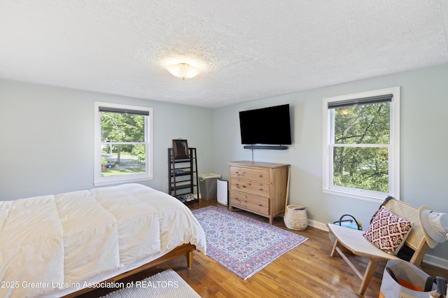 438 Bailey St, East Lansing, MI 48823 - bedroom with multiple windows, a textured ceiling, wood finished floors, and baseboards