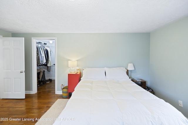 438 Bailey St, East Lansing, MI 48823 - bedroom with a walk in closet, wood finished floors, a closet, a textured ceiling, and baseboards