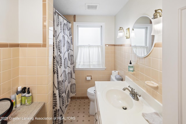 438 Bailey St, East Lansing, MI 48823 - full bath featuring tile walls, toilet, vanity, a shower with curtain, and a wainscoted wall