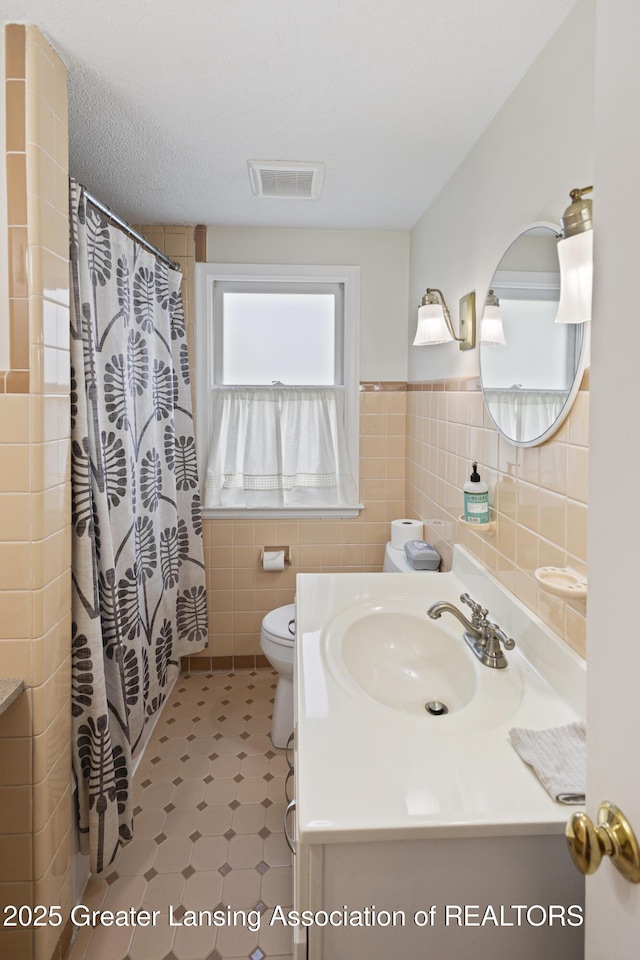 438 Bailey St, East Lansing, MI 48823 - bathroom featuring vanity, tile walls, toilet, a wainscoted wall, and curtained shower