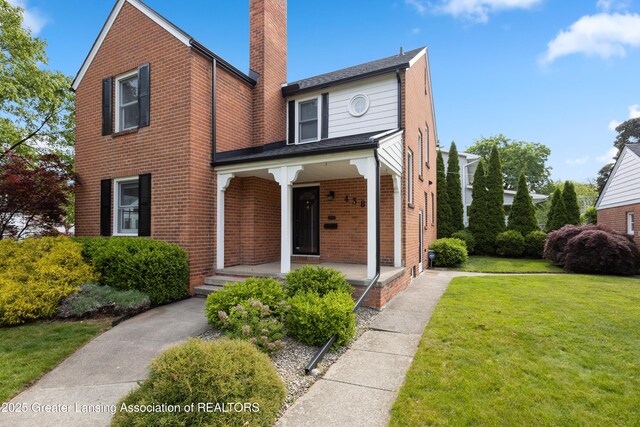 438 Bailey St, East Lansing, MI 48823 - view of front of home with covered porch, brick siding, a front yard, and a chimney