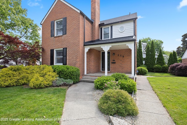 438 Bailey St, East Lansing, MI 48823 - traditional home featuring covered porch, brick siding, a chimney, and a front yard