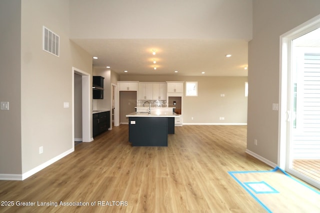 615 Magenta Ct, Haslett, MI 48840 - kitchen featuring white cabinets, light wood-type flooring, a sink, an island with sink, and open floor plan