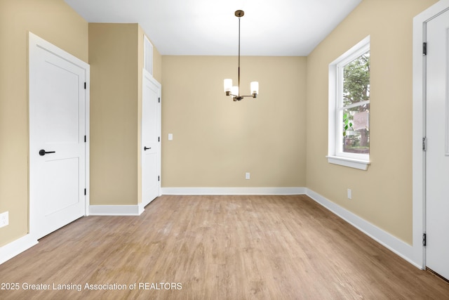 1221 W Saginaw St, Lansing, MI 48915 - unfurnished dining area featuring light wood-type flooring, a chandelier, and baseboards
