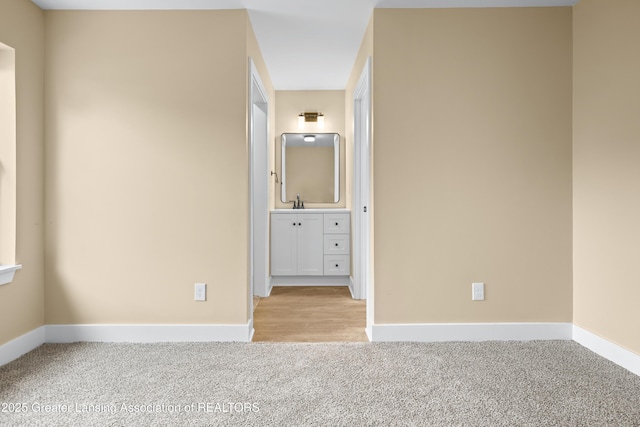 1221 W Saginaw St, Lansing, MI 48915 - unfurnished bedroom featuring light carpet, baseboards, connected bathroom, and a sink