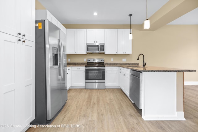 1221 W Saginaw St, Lansing, MI 48915 - kitchen with stainless steel appliances, a sink, a peninsula, light wood-type flooring, and dark stone counters