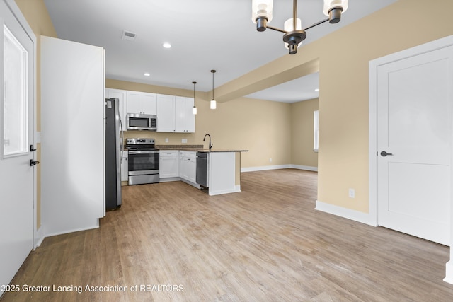 1221 W Saginaw St, Lansing, MI 48915 - kitchen with stainless steel appliances, open floor plan, a chandelier, a peninsula, and light wood-style flooring