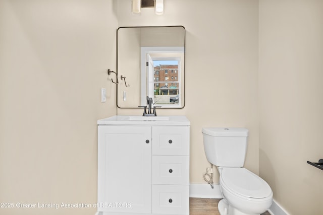 1221 W Saginaw St, Lansing, MI 48915 - half bath featuring baseboards, toilet, vanity, and wood finished floors