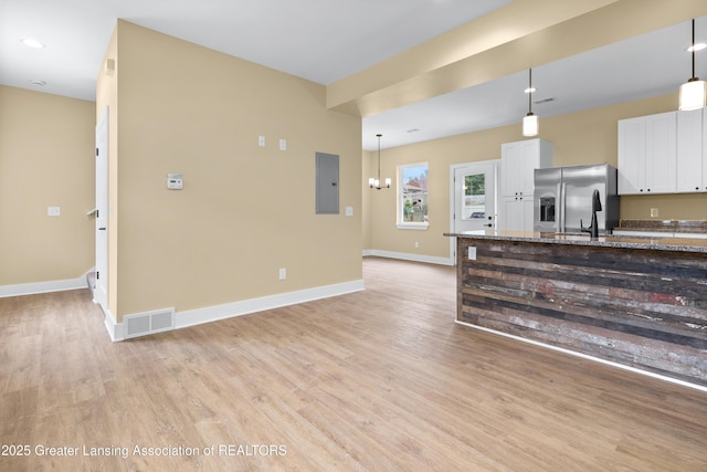 1221 W Saginaw St, Lansing, MI 48915 - kitchen featuring stainless steel fridge, electric panel, light wood-style flooring, baseboards, and white cabinetry