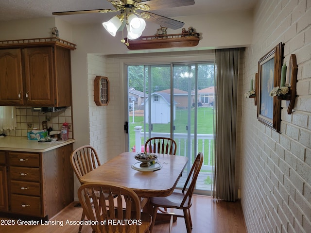 718 W Shepherd St, Charlotte, MI 48813 - dining room featuring light wood-style floors, ceiling fan, and brick wall