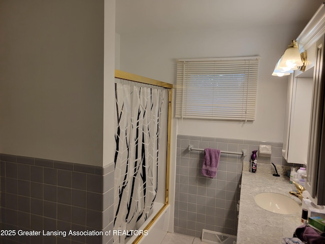 718 W Shepherd St, Charlotte, MI 48813 - full bathroom featuring tile walls, tile patterned flooring, vanity, shower / tub combo with curtain, and a wainscoted wall