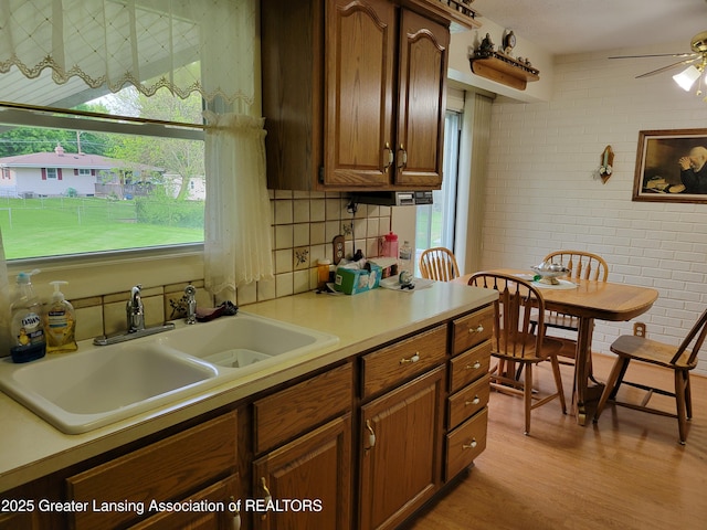 718 W Shepherd St, Charlotte, MI 48813 - kitchen featuring a sink, light wood finished floors, brick wall, ceiling fan, and light countertops