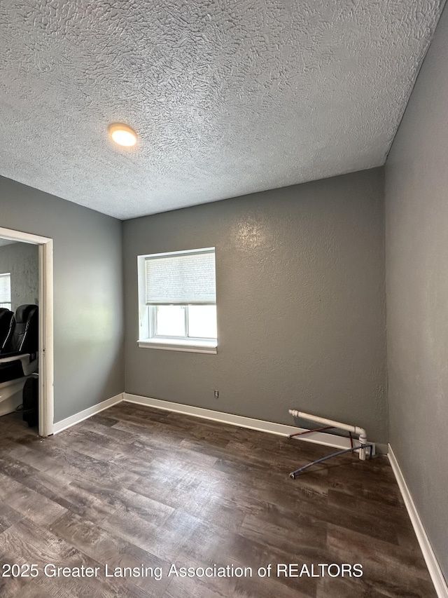 600 E Cavanaugh Rd, Lansing, MI 48910 - unfurnished bedroom with wood finished floors, a textured ceiling, and baseboards