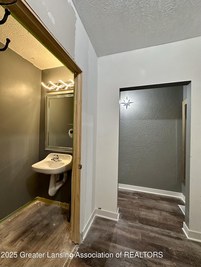 600 E Cavanaugh Rd, Lansing, MI 48910 - bathroom featuring wood finished floors, baseboards, a textured ceiling, and a sink