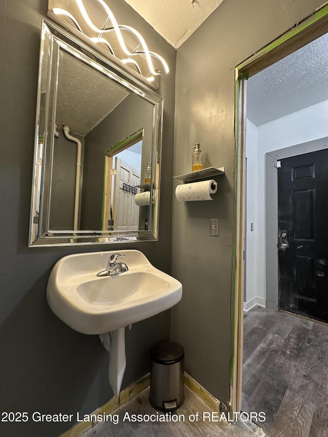 600 E Cavanaugh Rd, Lansing, MI 48910 - bathroom featuring a textured ceiling, a sink, baseboards, wood finished floors, and a chandelier