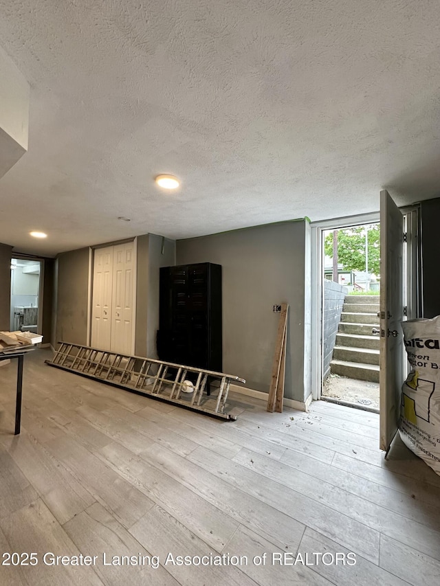 600 E Cavanaugh Rd, Lansing, MI 48910 - unfurnished living room featuring wood-type flooring, a textured ceiling, baseboards, and stairway