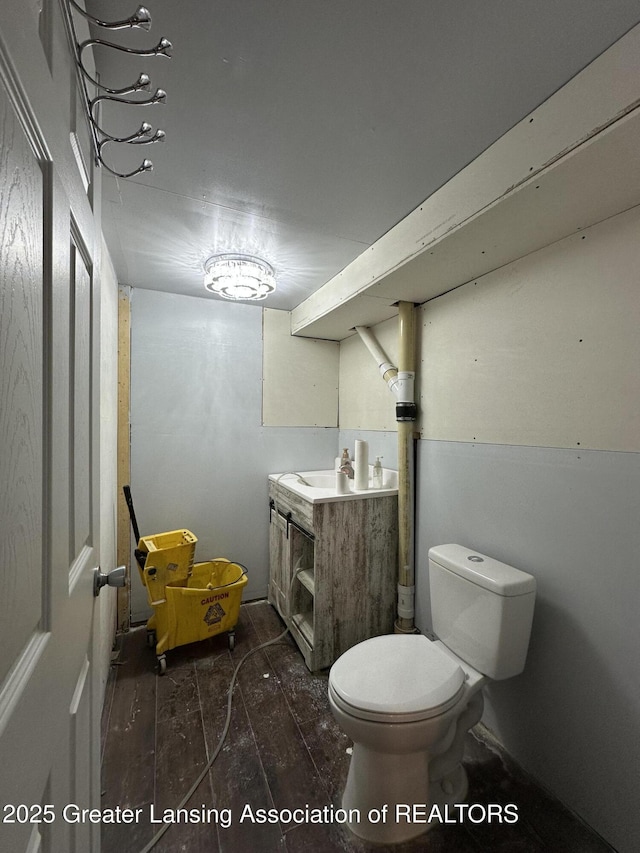 600 E Cavanaugh Rd, Lansing, MI 48910 - bathroom with toilet, vanity, and wood finished floors