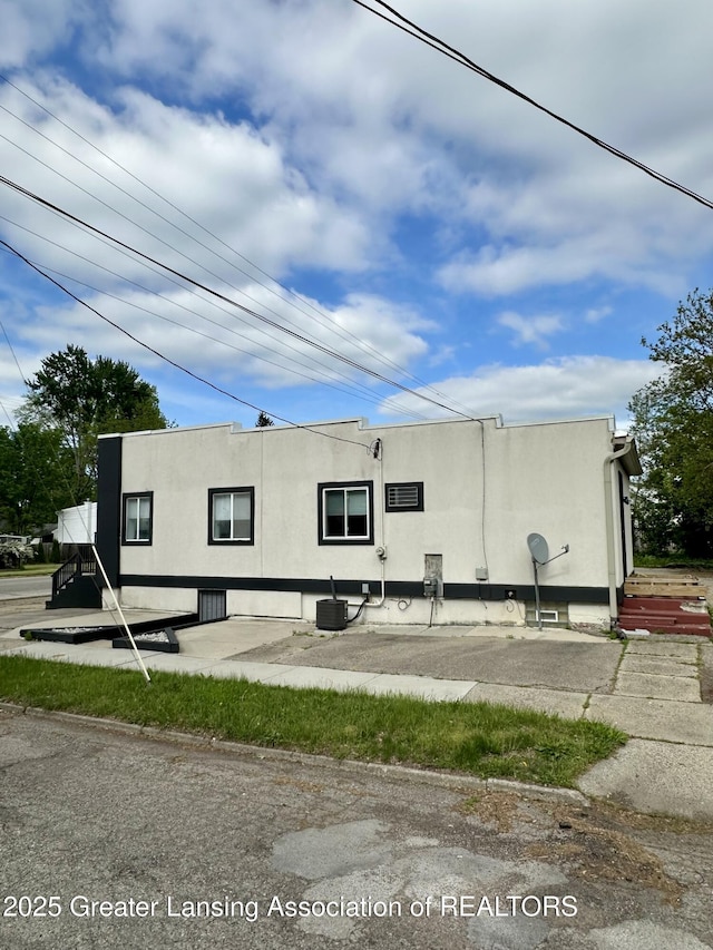 600 E Cavanaugh Rd, Lansing, MI 48910 - view of side of home featuring stucco siding