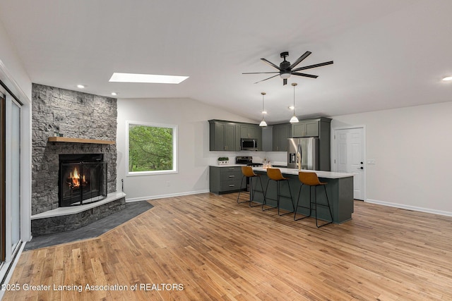 6420 Clise Rd, Bath, MI 48808 - kitchen featuring appliances with stainless steel finishes, light countertops, a skylight, a kitchen breakfast bar, and ceiling fan