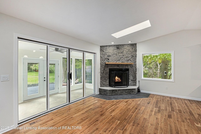 6420 Clise Rd, Bath, MI 48808 - unfurnished living room featuring wood finished floors, a skylight, lofted ceiling, and a stone fireplace