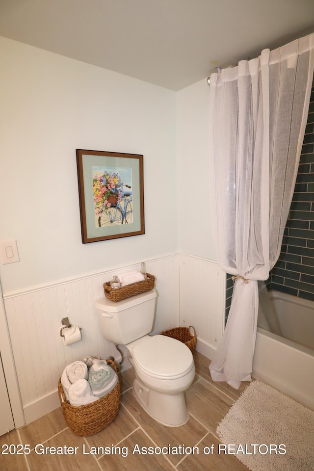 1615 Peppertree Ln, Lansing, MI 48912 - full bath featuring wood finished floors, toilet, a wainscoted wall, and shower / bathtub combination with curtain