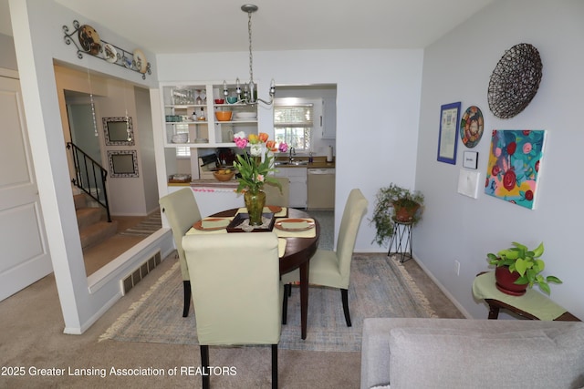 1615 Peppertree Ln, Lansing, MI 48912 - carpeted dining area with stairs, a chandelier, a sink, and baseboards