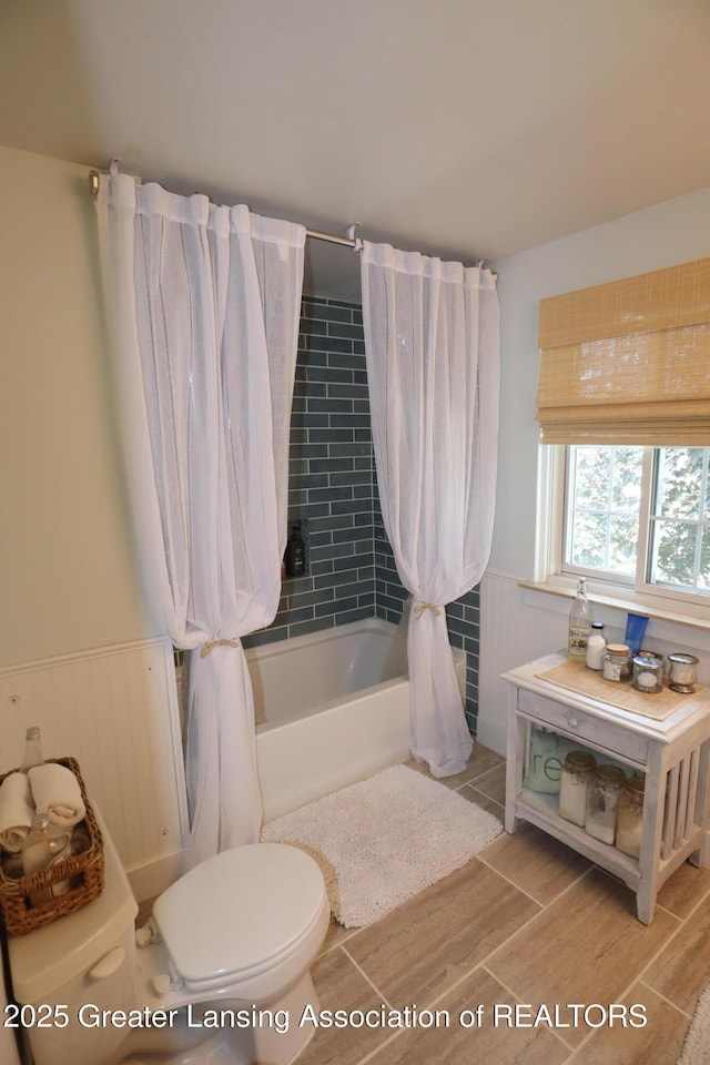 1615 Peppertree Ln, Lansing, MI 48912 - full bath featuring shower / bath combo with shower curtain, toilet, wood finished floors, and wainscoting