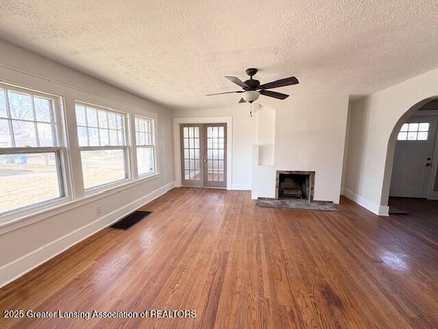 1305 W Hillsdale St, Lansing, MI 48915 - unfurnished living room with a textured ceiling, wood finished floors, arched walkways, baseboards, and a ceiling fan