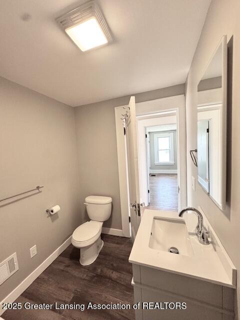 1305 W Hillsdale St, Lansing, MI 48915 - bathroom with toilet, wood finished floors, vanity, and baseboards