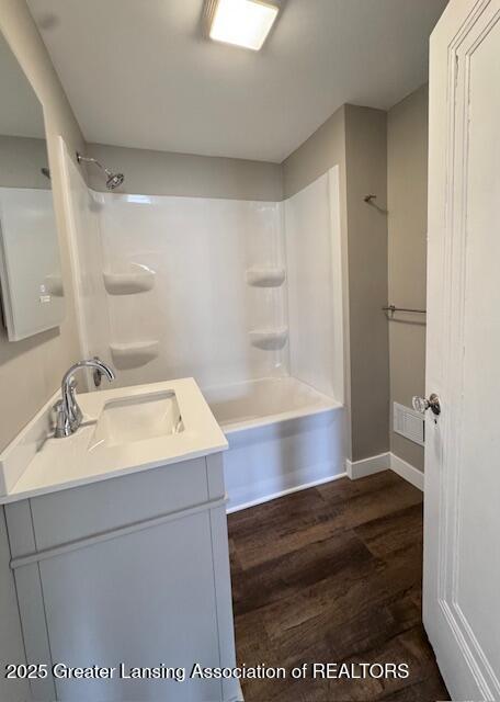 1305 W Hillsdale St, Lansing, MI 48915 - bathroom with wood finished floors, vanity, shower / washtub combination, and baseboards